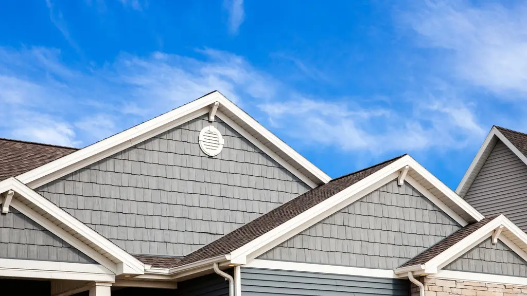 Grey siding, white trim and a gable vent on a shingled home